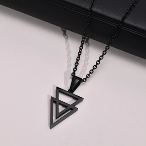 Macro shot of black geometric double triangle pendant and link chain on white surface