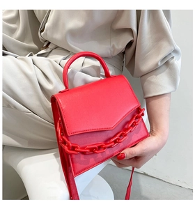 Detail of red small square crossbody bag with chunky chain and top handle on model