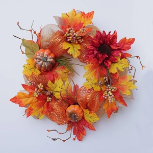 Detail of autumn wreath with faux sunflowers, pumpkins, maple leaves and berries on burlap