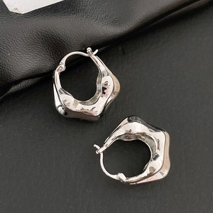 Vue macro de boucles d'oreilles géométriques argentées sur un fond de cuir noir texturé