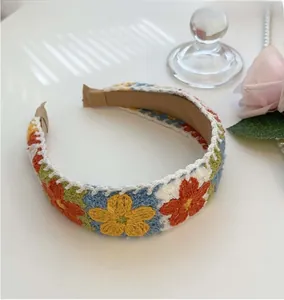Detail of handmade crochet floral headband with colorful knitted flower embroidery