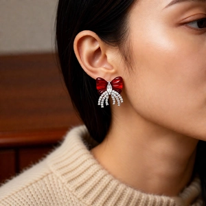 Detailed close-up of a vintage red bow ear cuff with zircon tassels on a model's ear