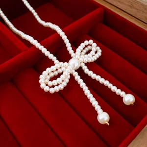 Close-up of pearl bow necklace in red velvet gift box with elegant golden accents