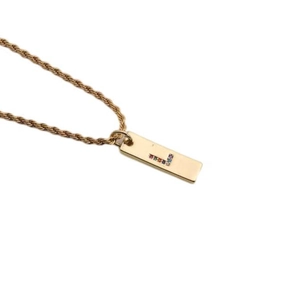 Macro shot of gold twist chain necklace with rainbow zircon letter L pendant detail