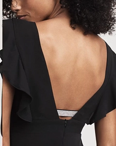 Detail showing deep V backless design with rhinestone strap and ruffles on black dress