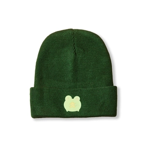 Close-up of deep green knit beanie featuring a cute cartoon frog embroidery patch