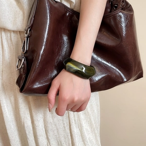 Detail of wide acrylic geometric cuff bracelet in marbled dark green and yellow