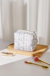 Detailed close-up of floral makeup bag with purple patterns and gold zipper on a tray