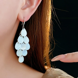 Close-up of layered white teardrop shell earrings with elegant fringe design