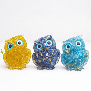 Detailed macro view of three crystal owl ornaments with gold leaf flakes on white background