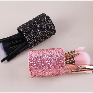 Detail view of pink and black glitter makeup brush holders with various cosmetic brushes