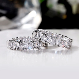 Close-up of sparkling silver drop-cut AAA zircon earrings on a reflective surface