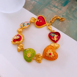 Macro shot of vintage style heart charms in gold finish with colorful enamel detailing