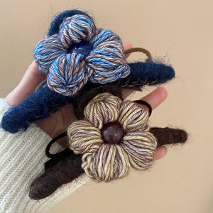 Détail de pinces à cheveux fleur en tricot avec pétales texturés et perle centrale
