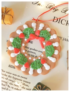 Detail of a gingerbread man wreath ornament with red ribbon on a vintage background