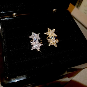 Macro detail of star-shaped earrings with zircon inlay on premium black velvet