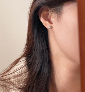 Close-up of a silver-gray pearl stud earring worn on model for a minimalist style