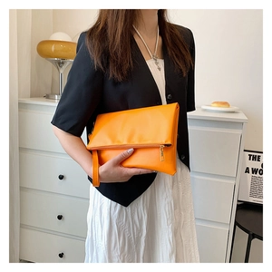 Detalle de un bolso de mano de cuero naranja brillante con correa y cremallera