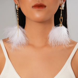 Close-up of elegant gold chain earrings with white feather tassels and sparkling rhinestones