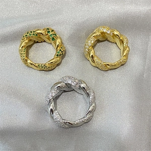Macro detail of twisted gold and silver rings set with sparkling green and white zircon