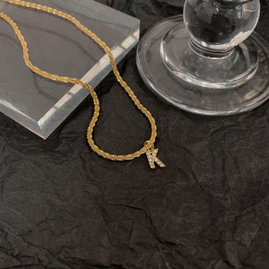 Détail du collier plaqué or avec un pendentif étincelant en forme de lettre K serti