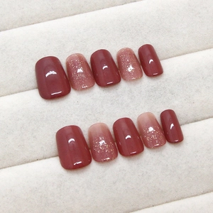 Short square burgundy and glitter press-on nails set displayed on a beige tray