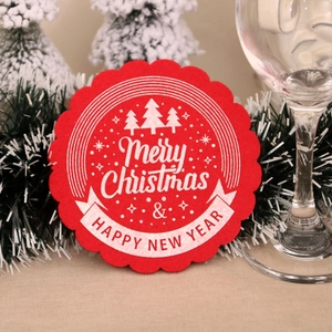 Detail of red felt Christmas coaster with white snowflake patterns and festive lettering