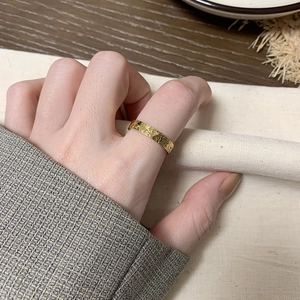 Close-up of a gold-plated titanium ring with textured dragon scale pattern on a finger