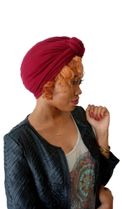 Close-up of red elastic knit turban hat showing detailed fabric texture on a model