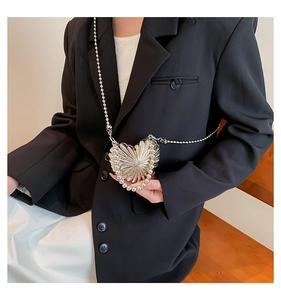 Silver heart-shaped metallic crossbody bag with shell texture on a black blazer