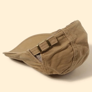 Detail view of khaki cotton flat cap featuring adjustable bronze metal buckle and stitching