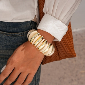 Detail of chunky acrylic elastic bracelet with gold and marble resin links on wrist