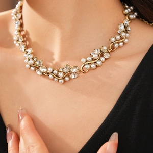 Close-up of vintage gold necklace with oval pearls and rhinestones on a model