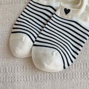 Detailed close-up of striped boat socks with heart embroidery on breathable cotton fabric