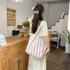 Lifestyle view of large red and white striped canvas tote bag in a cozy cafe setting