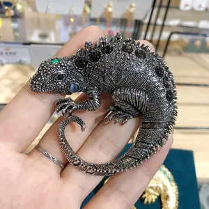 Detailed view of a vintage chameleon brooch with black rhinestones and green emerald gems