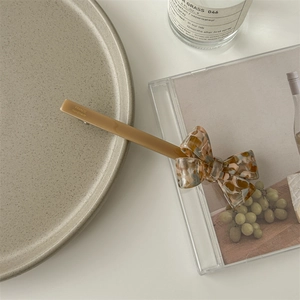 Detail view of handmade beige acetate bow hair clip with colorful printed pattern