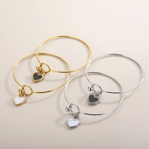 Goldenes und silbernes Armreifen-Set mit Herzanhängern aus Emaille auf beigem Hintergrund
