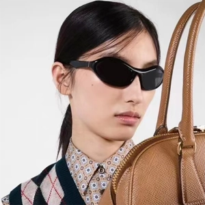 Nahaufnahme der schwarzen Sportsonnenbrille kombiniert mit einer braunen Lederhandtasche