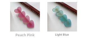 Close-up of heart-shaped hair clips in peach pink and light blue with matte finish