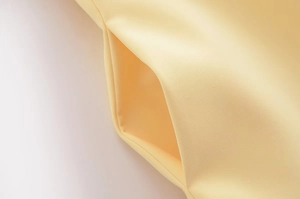 Detail shot of a side pocket on a summer dress in light yellow fabric with clean texture