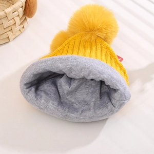 Yellow knitted baby winter hat with grey fleece lining and dual faux fur pom-poms