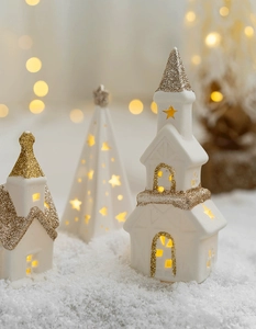 Detail of ceramic Christmas house with warm LED light and golden glitter finish