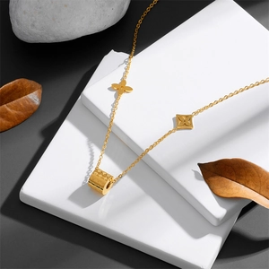 Detailed shot of golden pendant with cylindrical and floral charms on white stone