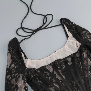 Détail d'un haut corset en dentelle noire avec mesh transparent et baleines de soutien
