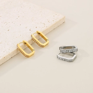 Macro shot of U-shaped stainless steel earrings with emerald-cut zircon in gold and silver