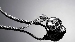 Detailed view of silver skull pendant with box chain on a reflective professional background