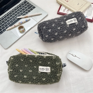 Detail of plush lamb-like fabric pencil case with flower embroidery and plaid handle
