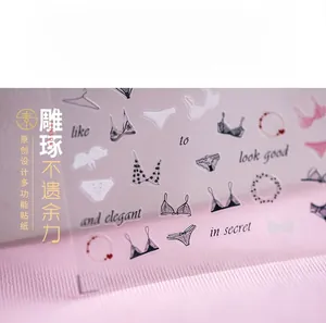 Macro shot of 5D thin nail stickers with black lace and heart motifs on pink fabric