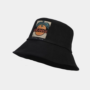 Détail d'un bob noir avec motif d'orange et inscription typographique style pastoral